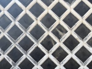 Traditional Japanese "namako" wall featuring raised white plaster lines and dark tiles forming a geometric diamond pattern.